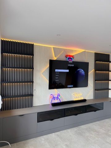 Completed bespoke media wall with floating storage cabinets, ambient LED lighting and custom slatted feature panels installed by Furnitureistic in Hertfordshire