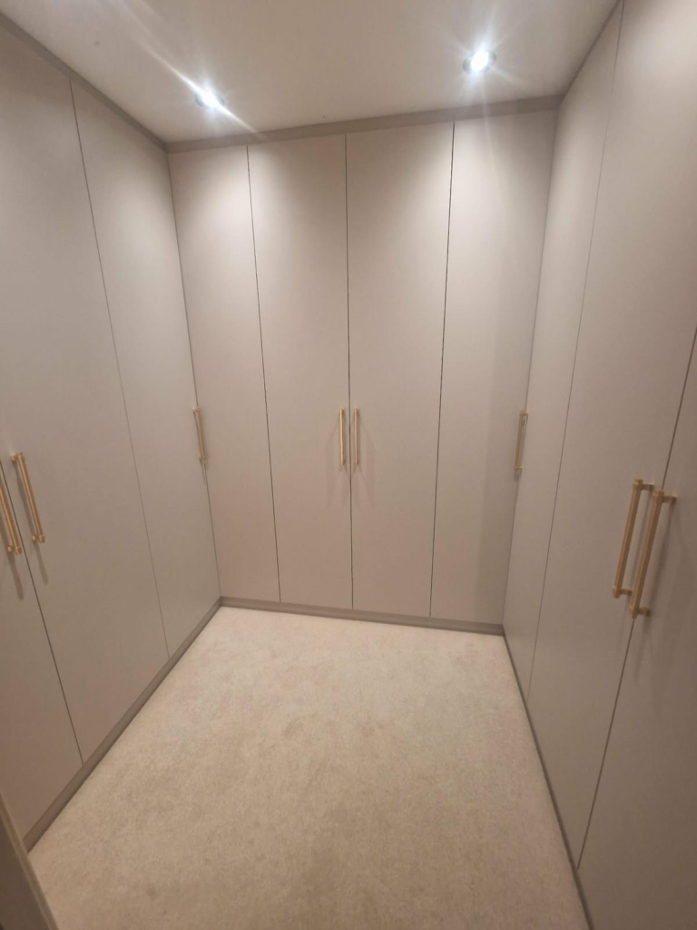 Completed bespoke walk-in wardrobe in Stanmore with floor-to-ceiling Cashmere Grey cabinets and elegant gold handles