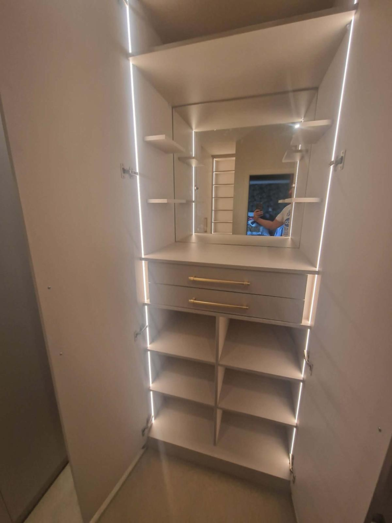 Bespoke walk-in wardrobe corridor with integrated LED shoe shelving and Cashmere Grey fitted cabinets in Stanmore